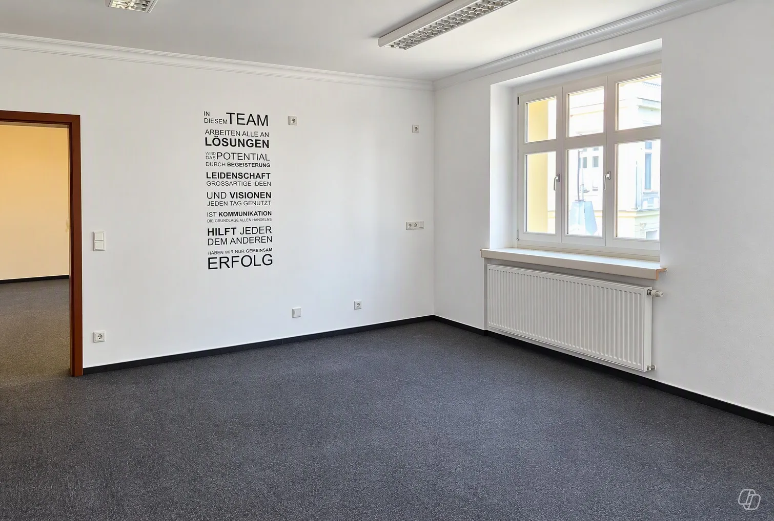 Helles Büro mit großen Fenstern, Heizkörpern und dunklem Teppichboden